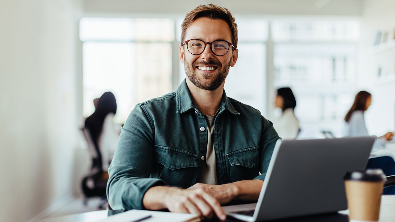 Man with glasses working on a laptop